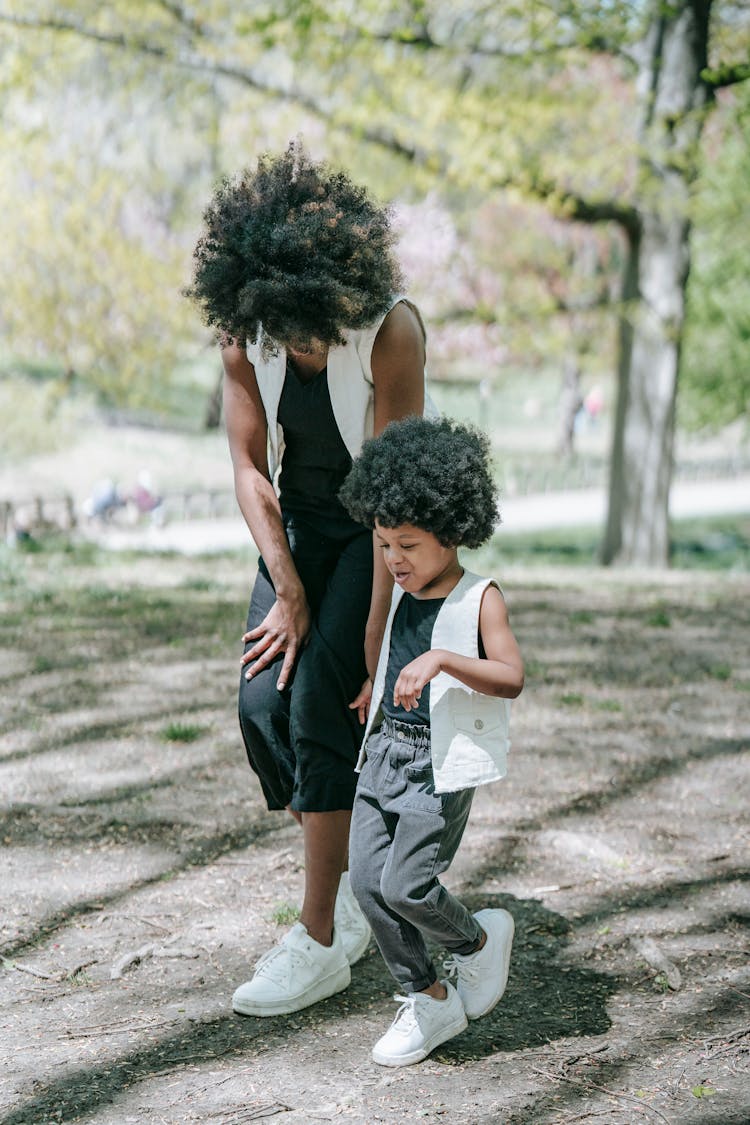 A Woman And A Child With Matching Outfits Walking At A Park