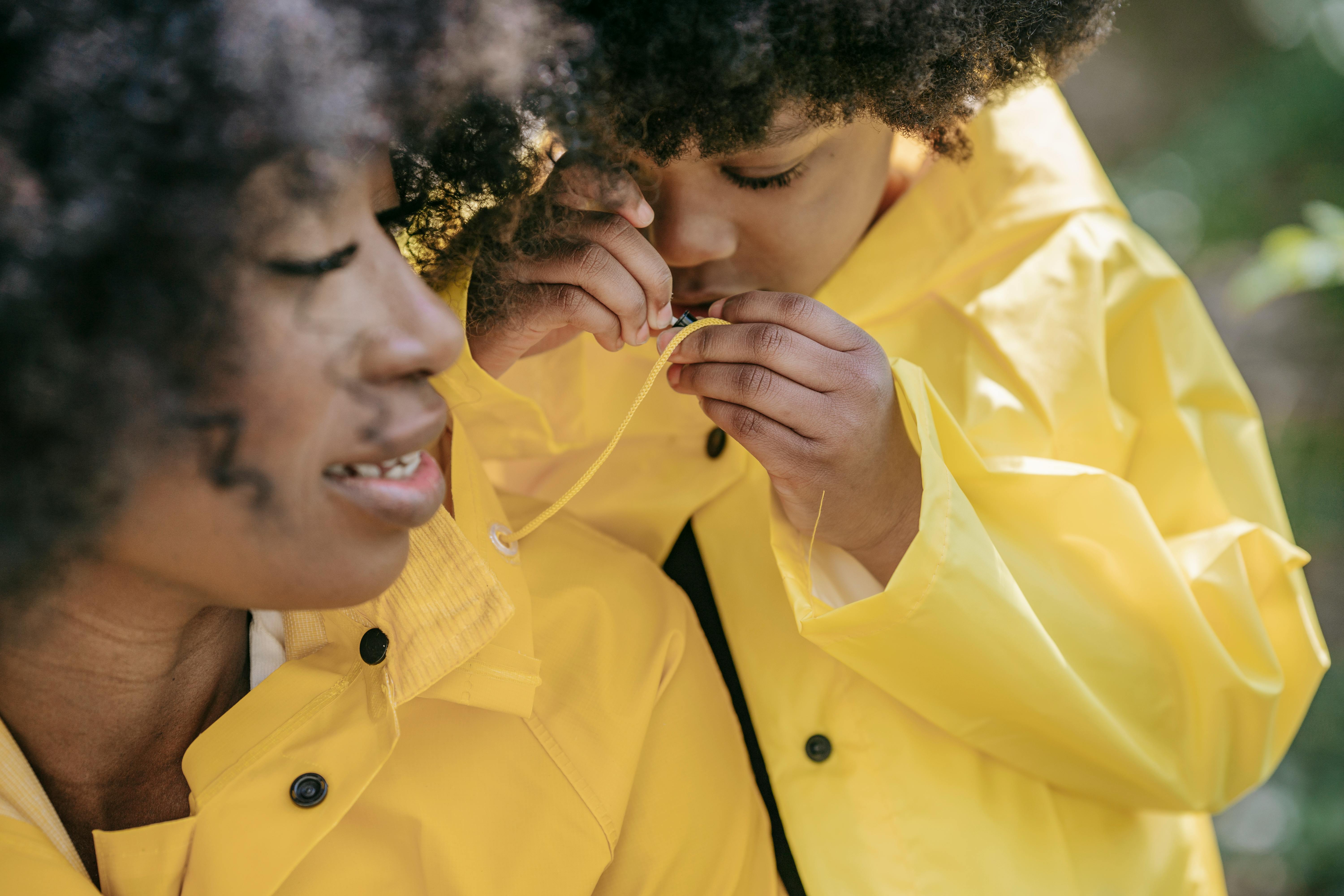 A mother and daughter in yellow raincoats enjoying a moment in nature.