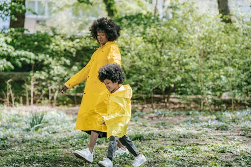 A Woman and a Child with Matching Raincoats Walking at a Park