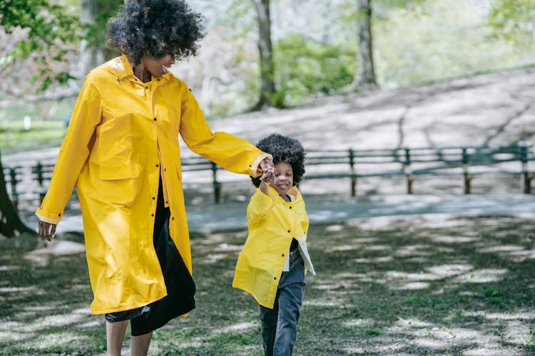 A Woman Holding A Young Girl's Hand While Running On The Park