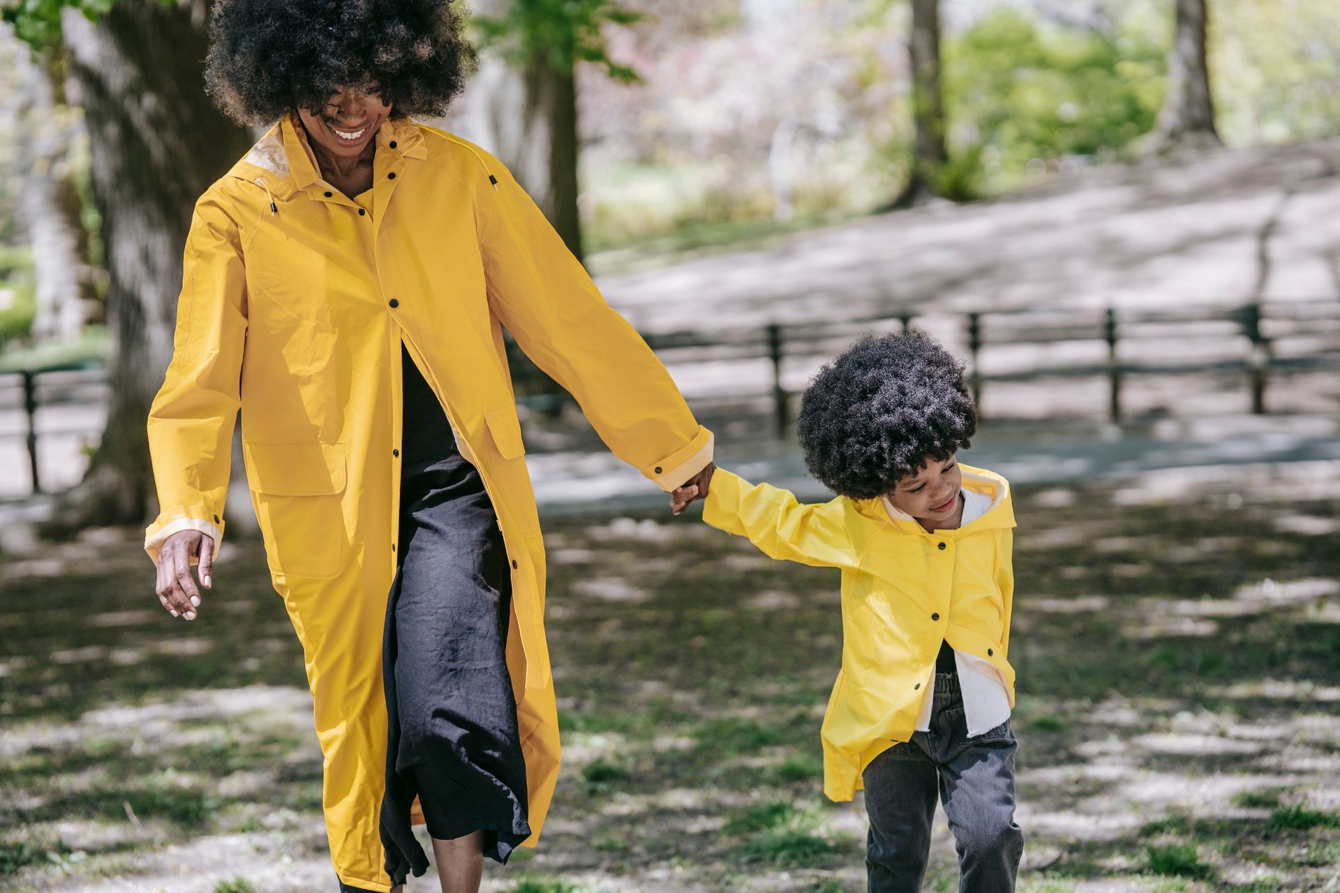 A mother and child enjoy a sunny day wearing stylish matching yellow raincoats.