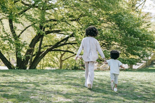 Free A Woman and her Child Holding Hands While Walking at a Park Stock Photo