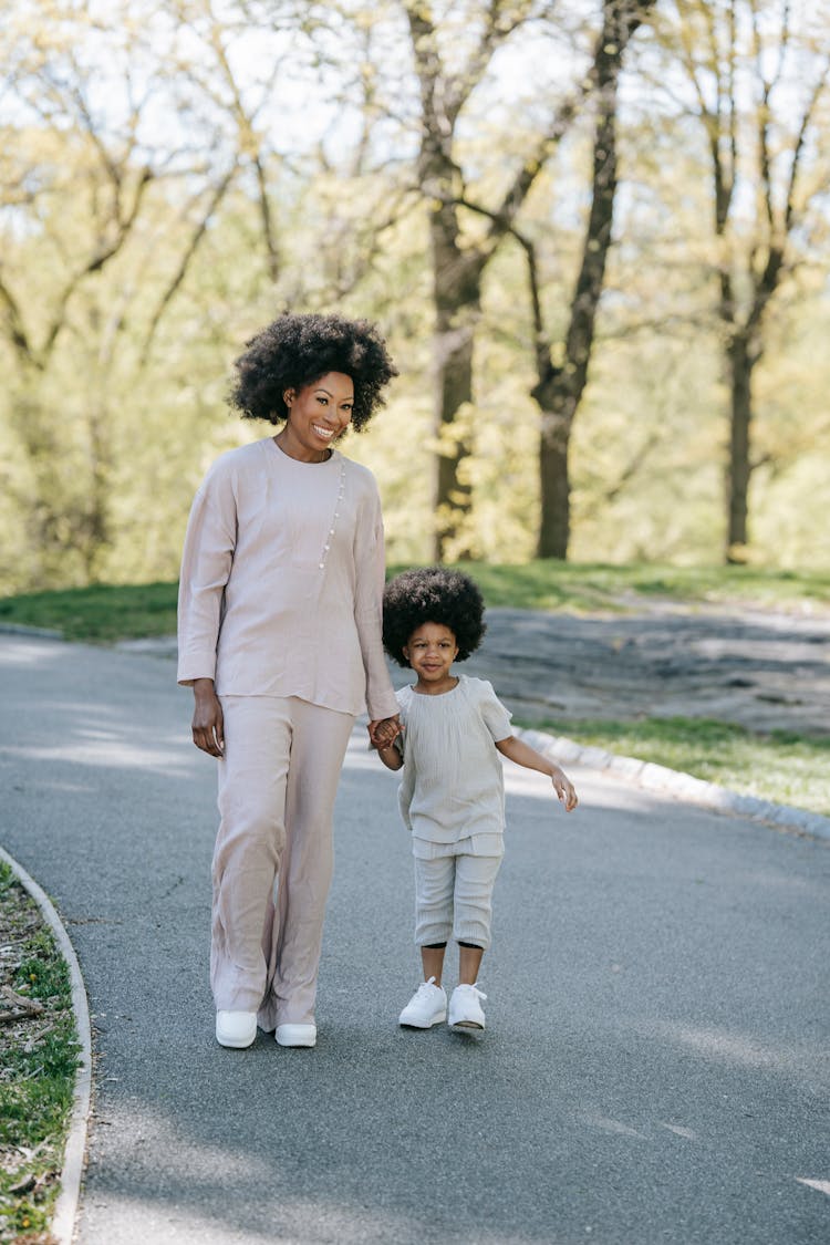 Mother And Daughter Walking Along Footpath In A Park