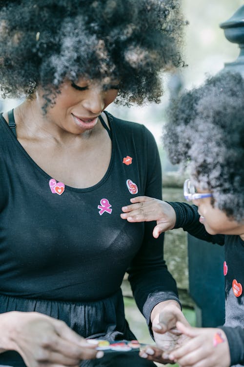 Free A Child Putting Stickers on Woman's Black Long Sleeves Stock Photo