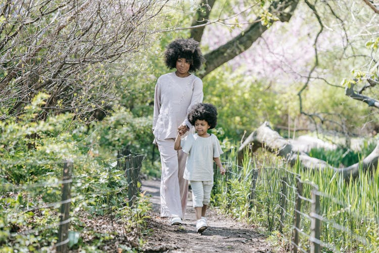 A Woman And A Young Girl Holding Hands While Walking 