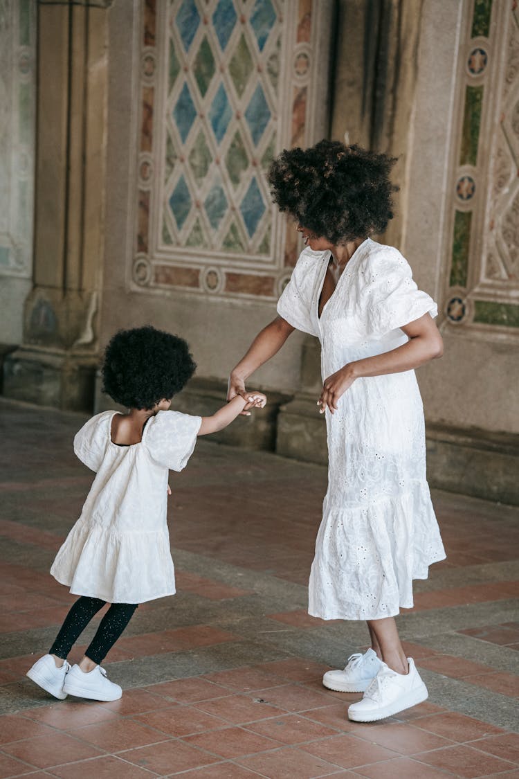 Mother And Her Daughter Dancing Together On Concrete Floor