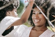 Smiling Woman in White Floral Lace Dress Holding a Child