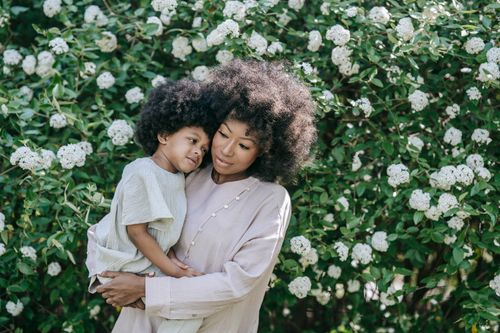 Free A loving moment between a mother and daughter surrounded by blooming flowers in spring. Stock Photo