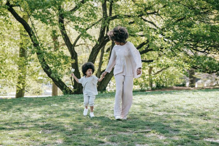 Mother and daughter walking hand in hand in a park