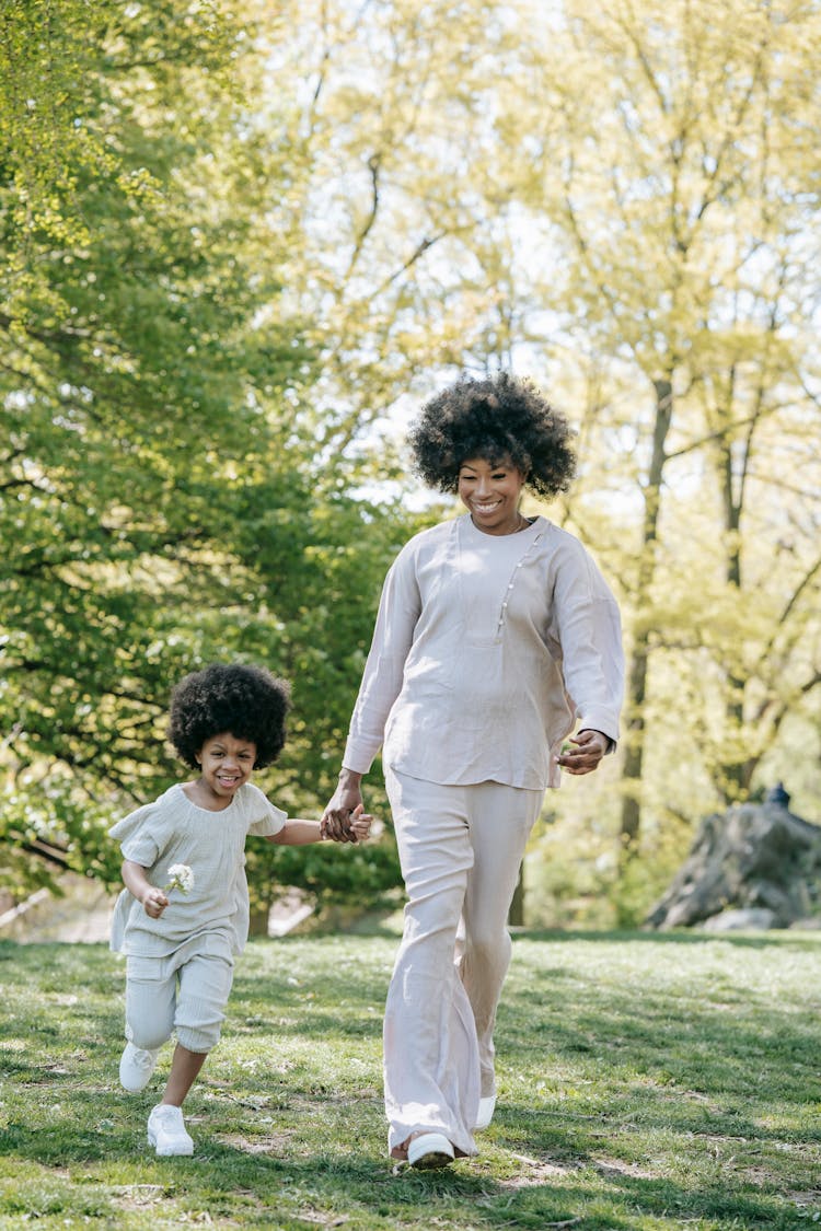 A Woman Walking At The Park With Her Daughter While Holding Hands