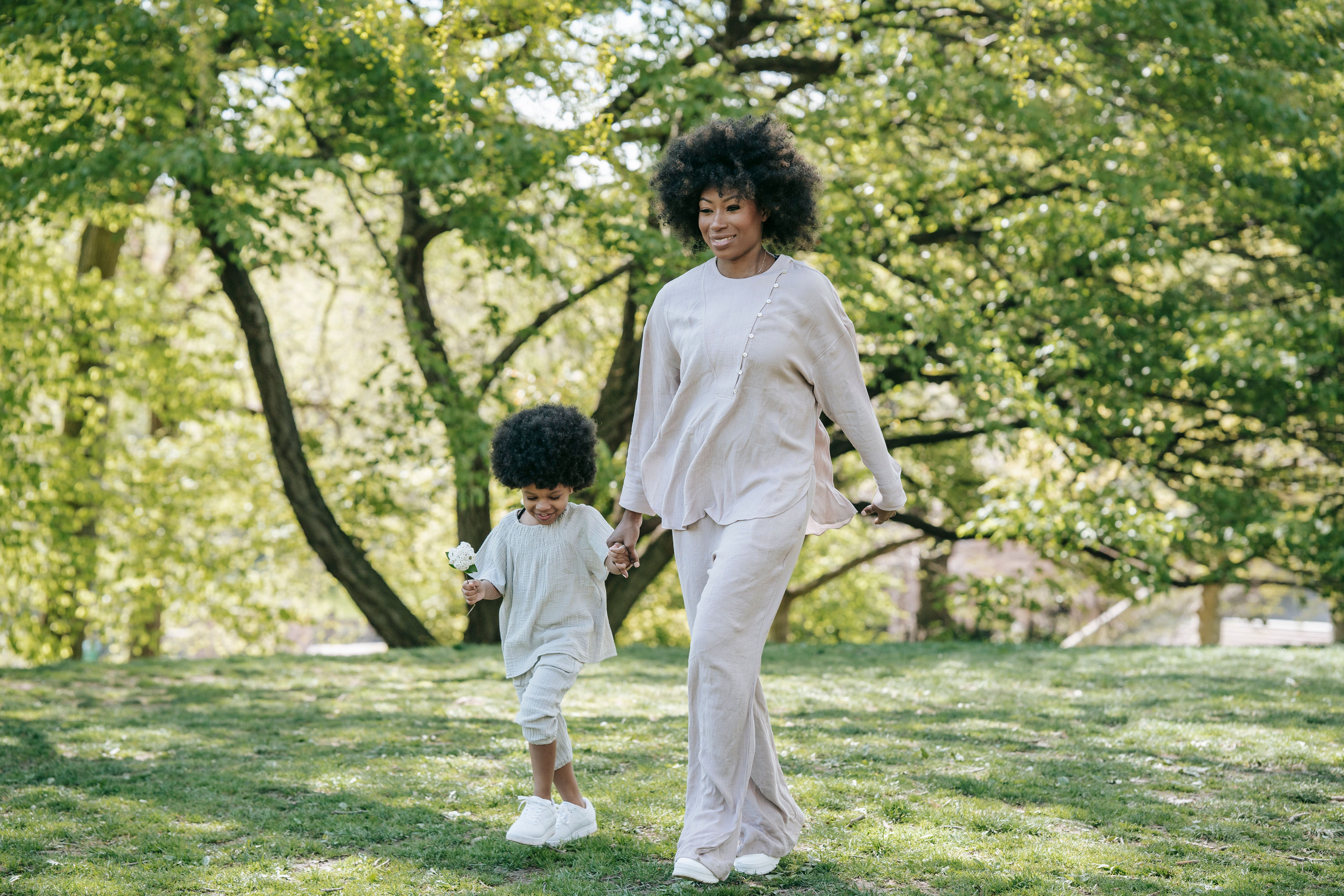 A Woman Walking at the Park with Her Daughter while Holding Hands ...