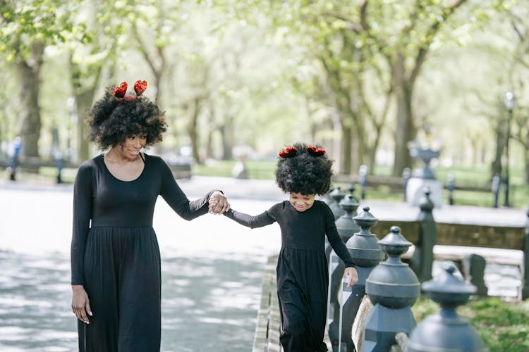 A Woman And A Young Girl Walking On The Park