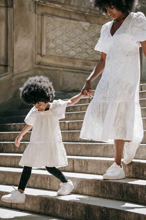 A Woman and a Girl Holding their Hands while Going Down on Stairs