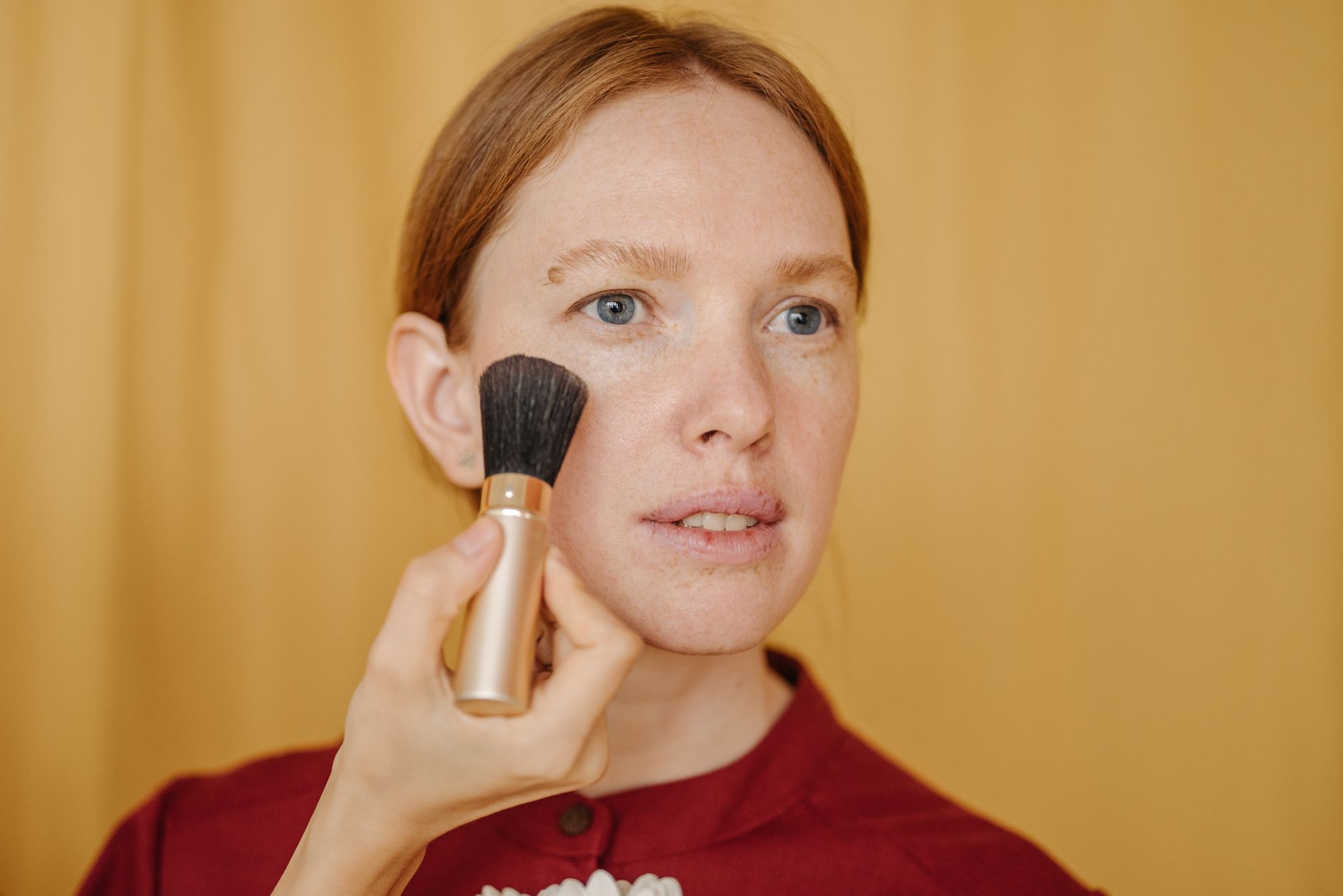 Close-up of a woman applying makeup with a brush in a studio setting.