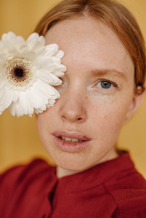 Portrait of a Woman's Face with Freckles Beside a White Flower