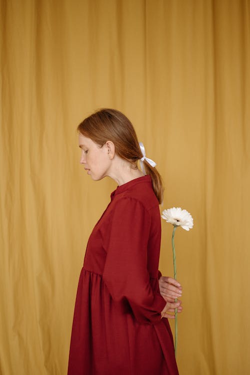 A Woman in Red Dress Holding a White Flower Behind Her