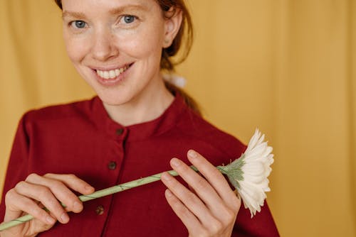 Free Close-Up Photo of a Woman with Freckles Smiling while Holding a Flower Stock Photo