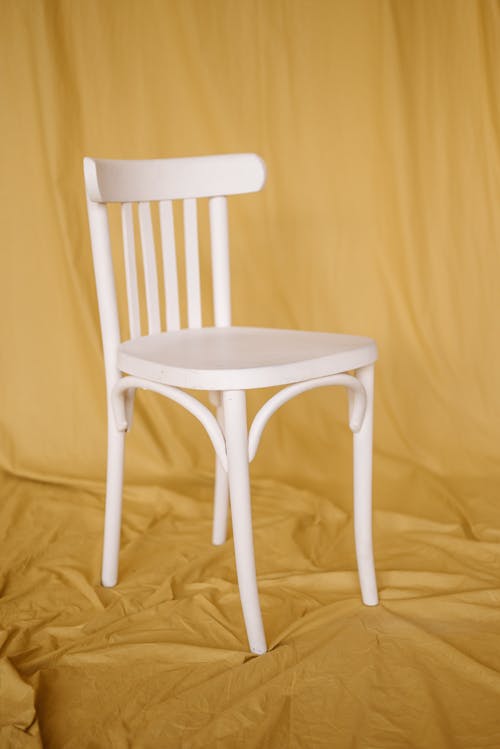 Free Photo of a White Chair on a Mustard Cloth Stock Photo