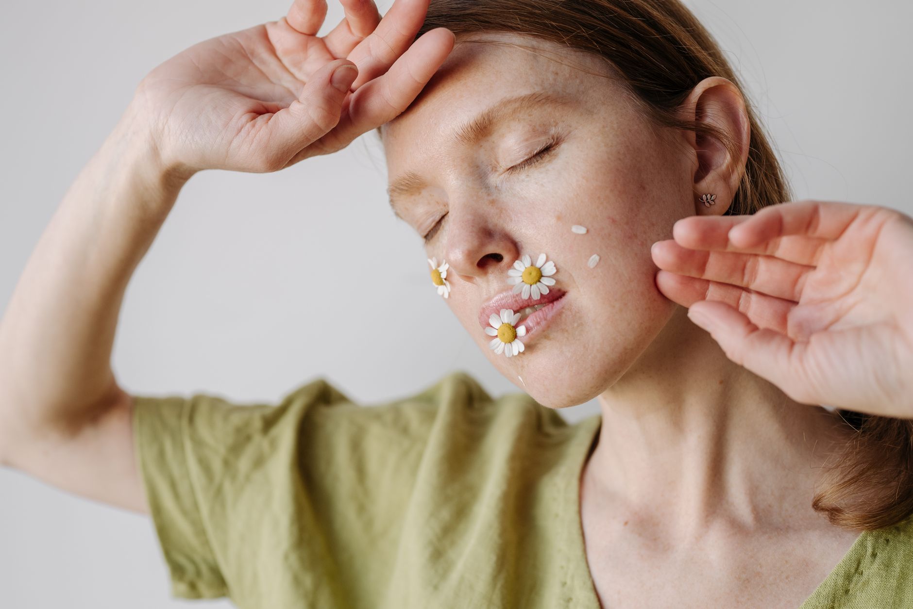 Creative portrait of a woman with daisies on her face expressing serenity and contemplation.