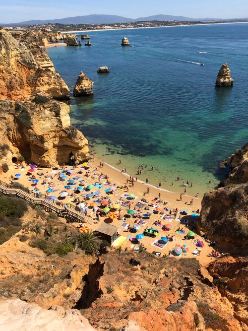 Free A breathtaking aerial shot of Algarve beach with sunbathers, rocks, and vibrant umbrellas. Stock Photo