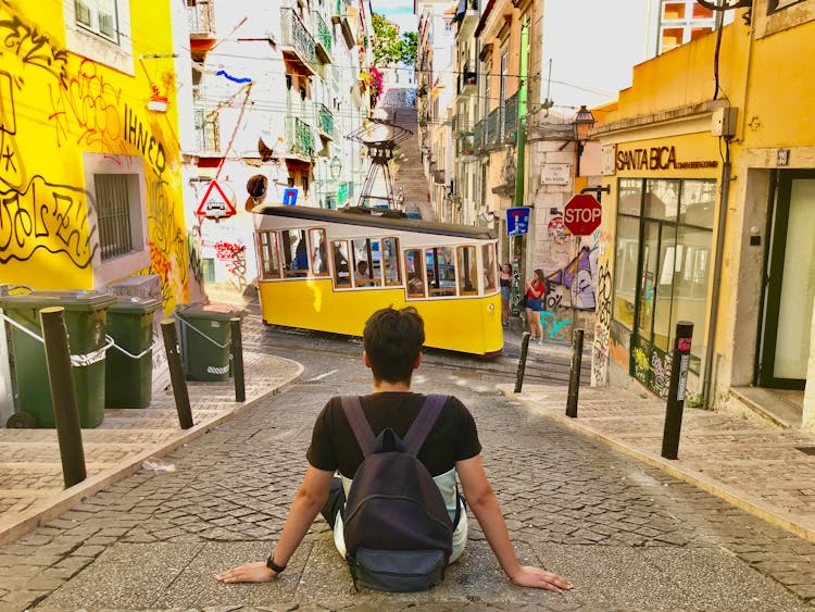 Backpacker Looking At Street Car In City