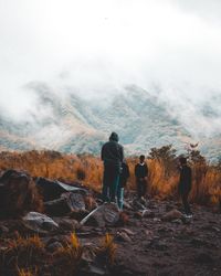 Walkers on a rocky path under low cloud, photo by Rifqi Ramadhan on Pexels