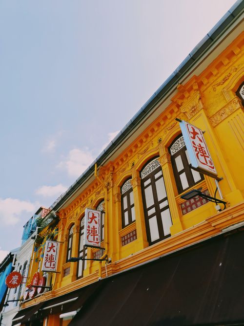 Free Low-angle shot of a bright yellow traditional Asian building with prominent signage and ornate details. Stock Photo