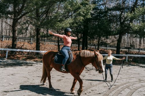 Free Woman practices riding techniques in a park setting, emphasizing balance and skill development. Stock Photo