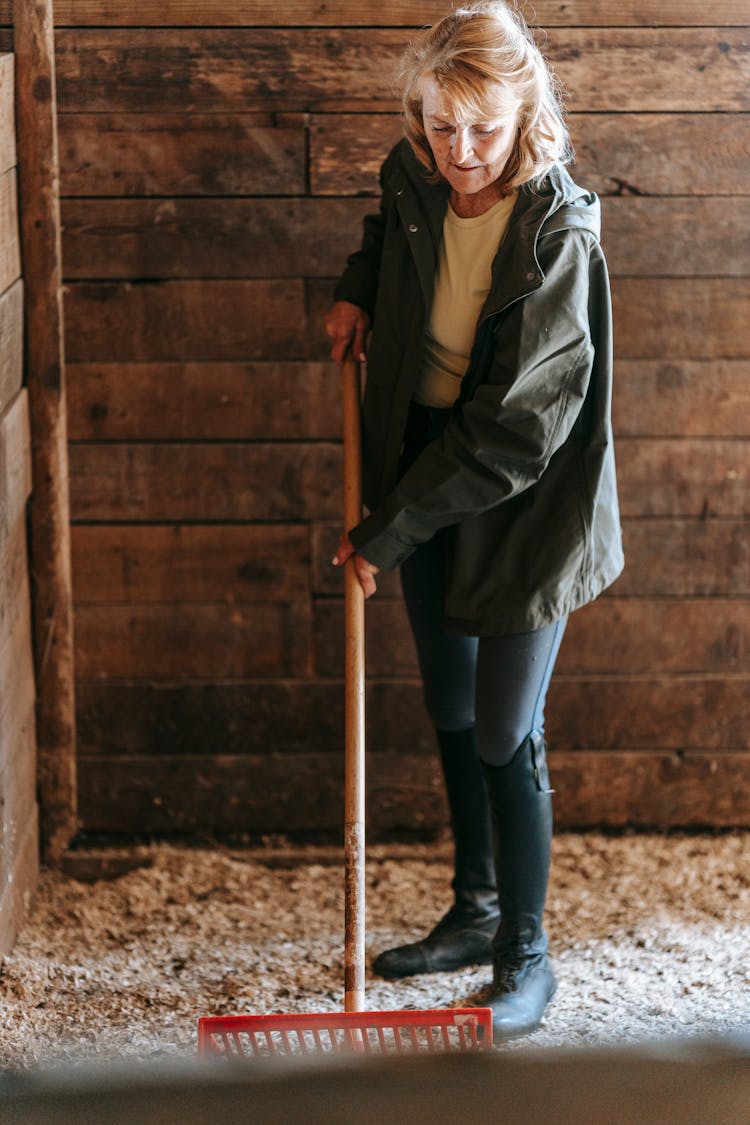 Woman Wearing A Jacket Holding A Rake