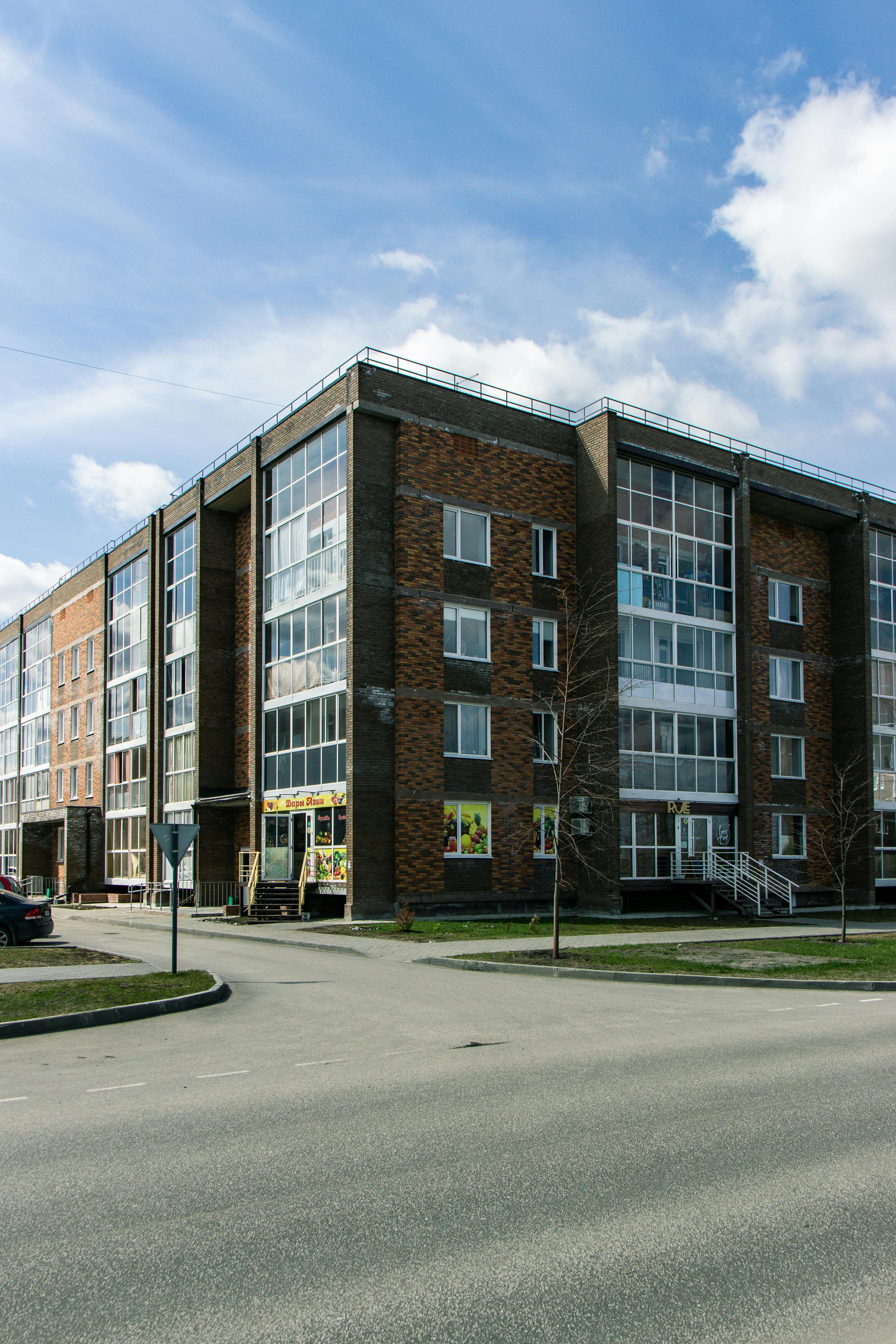 Free Four-story brick building with glass windows, captured on a clear day. Stock Photo