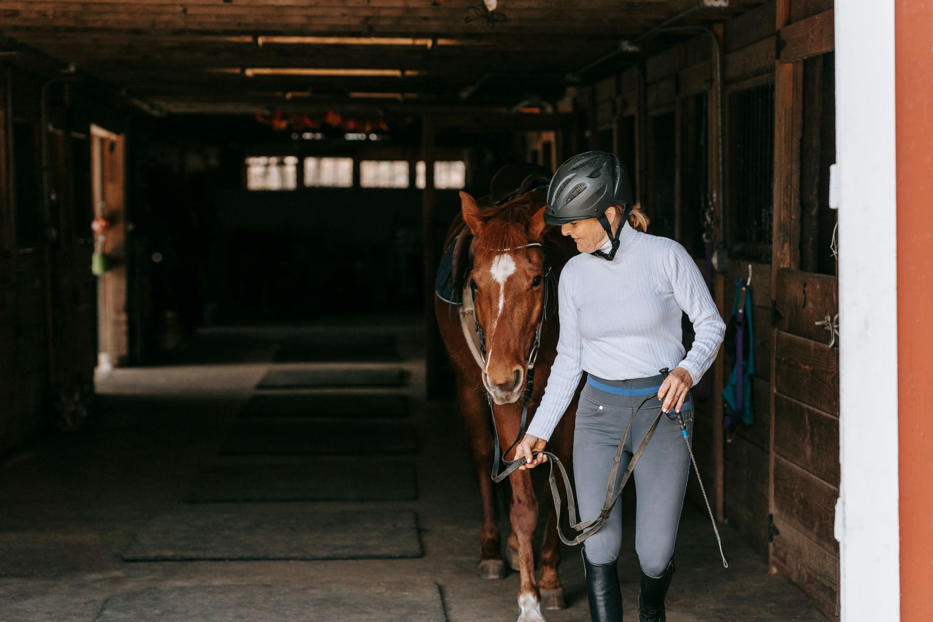 Smiling Woman Leading Horse out of Stable
