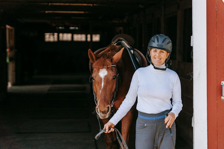 Woman Leading A Horse Out Of The Stable