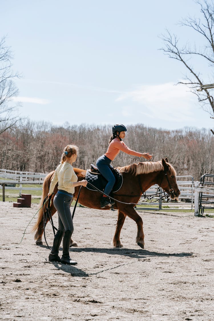 Women Riding A Horse With An Instructor