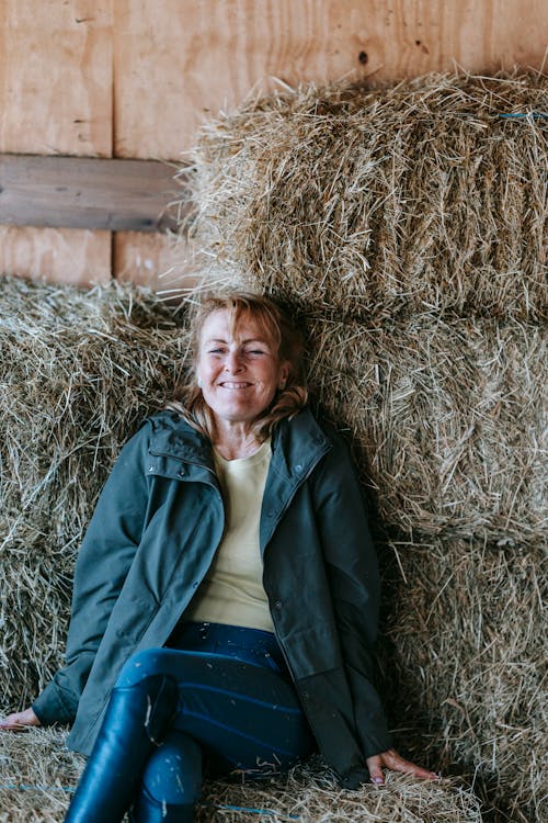 Free A Woman Smiling Sitting on a Haystack Stock Photo