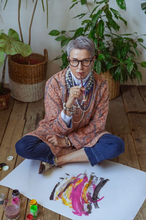 Free Elderly woman artist contemplating her abstract painting in a cozy studio setting. Stock Photo
