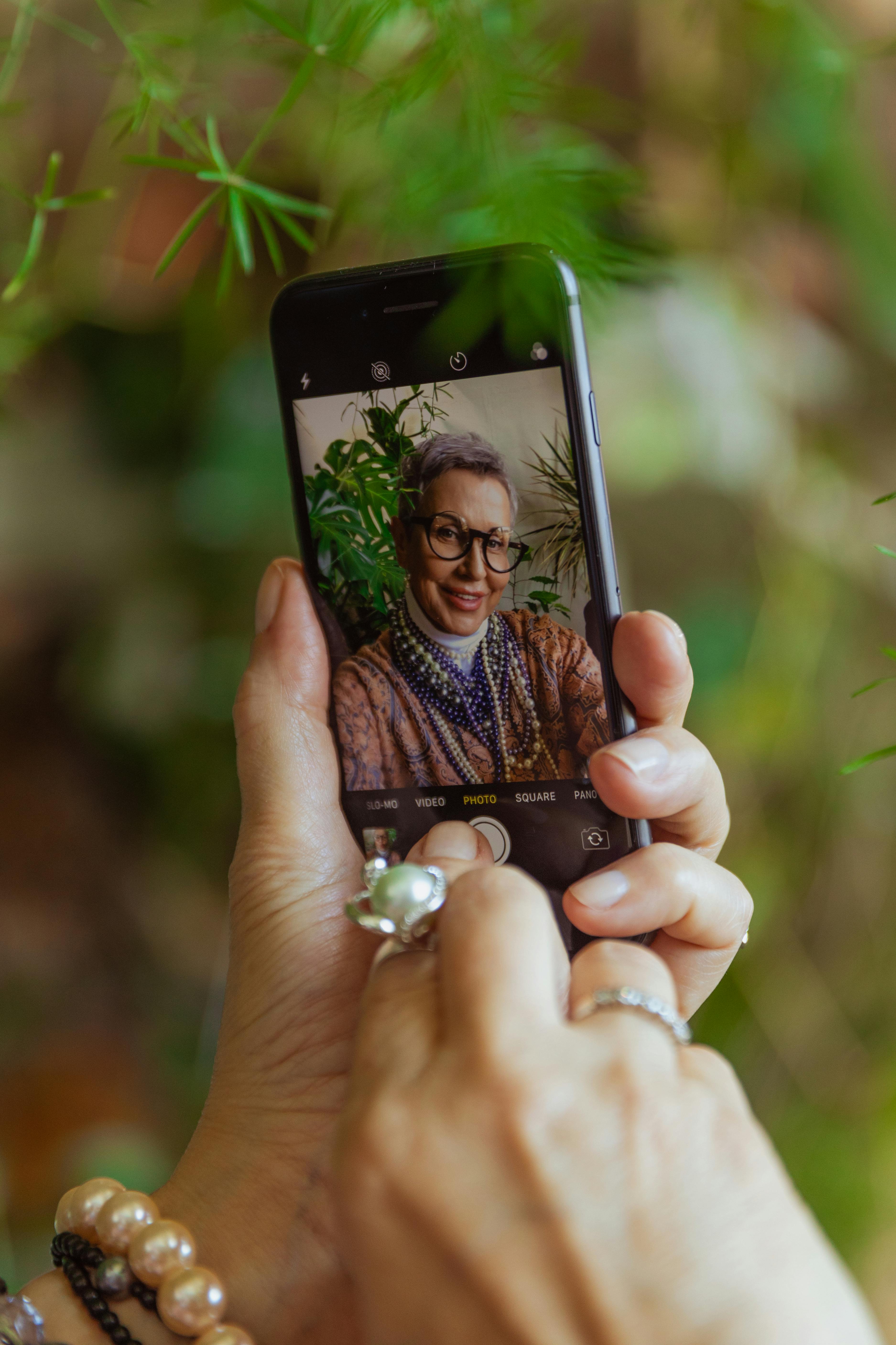 A senior woman taking a selfie outdoors, showcasing personality and modern technology.