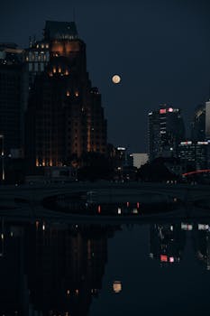 Captivating cityscape with moonlit reflections over a river at night.