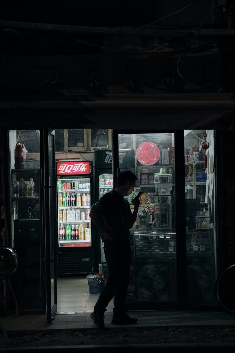 Photo Of A Man Using His Phone In Front Of A Store