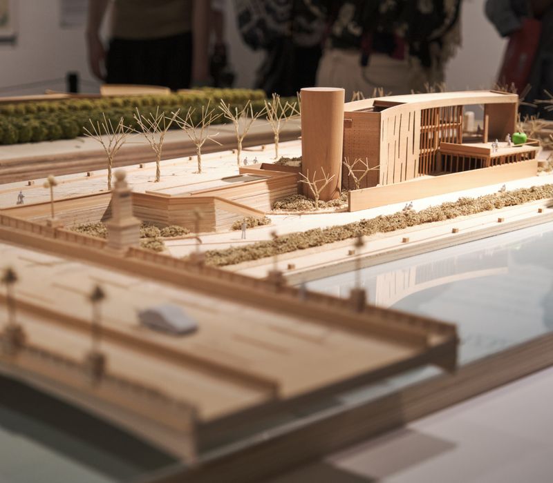 Detailed wooden architectural scale model displayed in an exhibition environment.