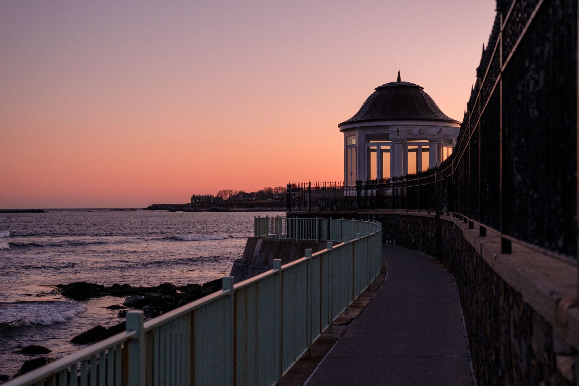 Charming coastal walkway with gazebo by the ocean at sunset in Rhode Island.