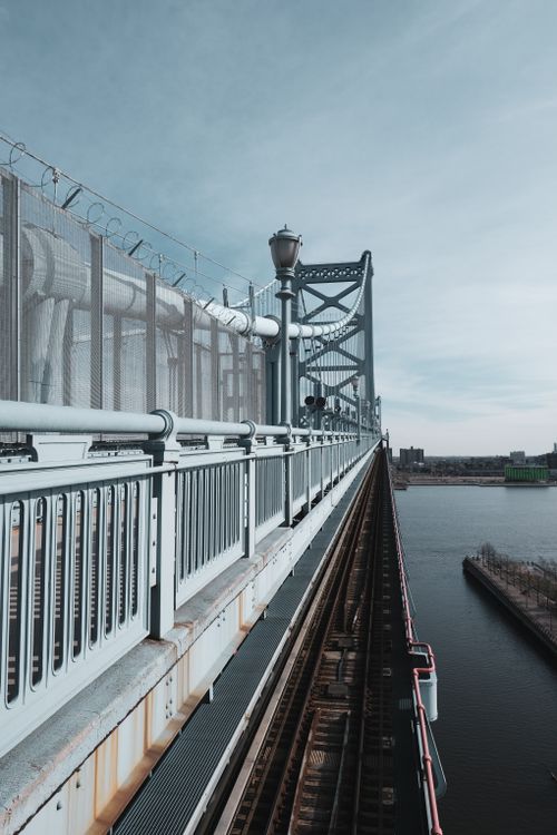 Free Stunning perspective of a suspension bridge over calm waters on a clear day. Stock Photo