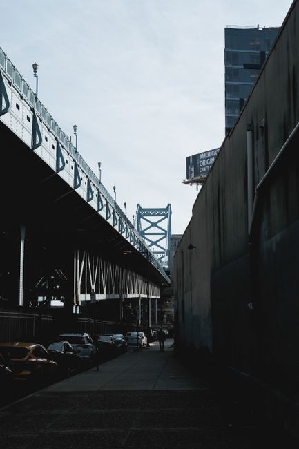 Dynamic street scene with cars and a suspension bridge under a clear sky.