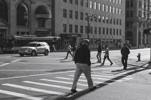 Free Black-and-white city scene with pedestrians crossing a street. Stock Photo