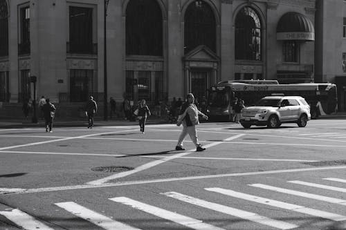 Grayscale Photo of People Crossing on Pedestrian Lane