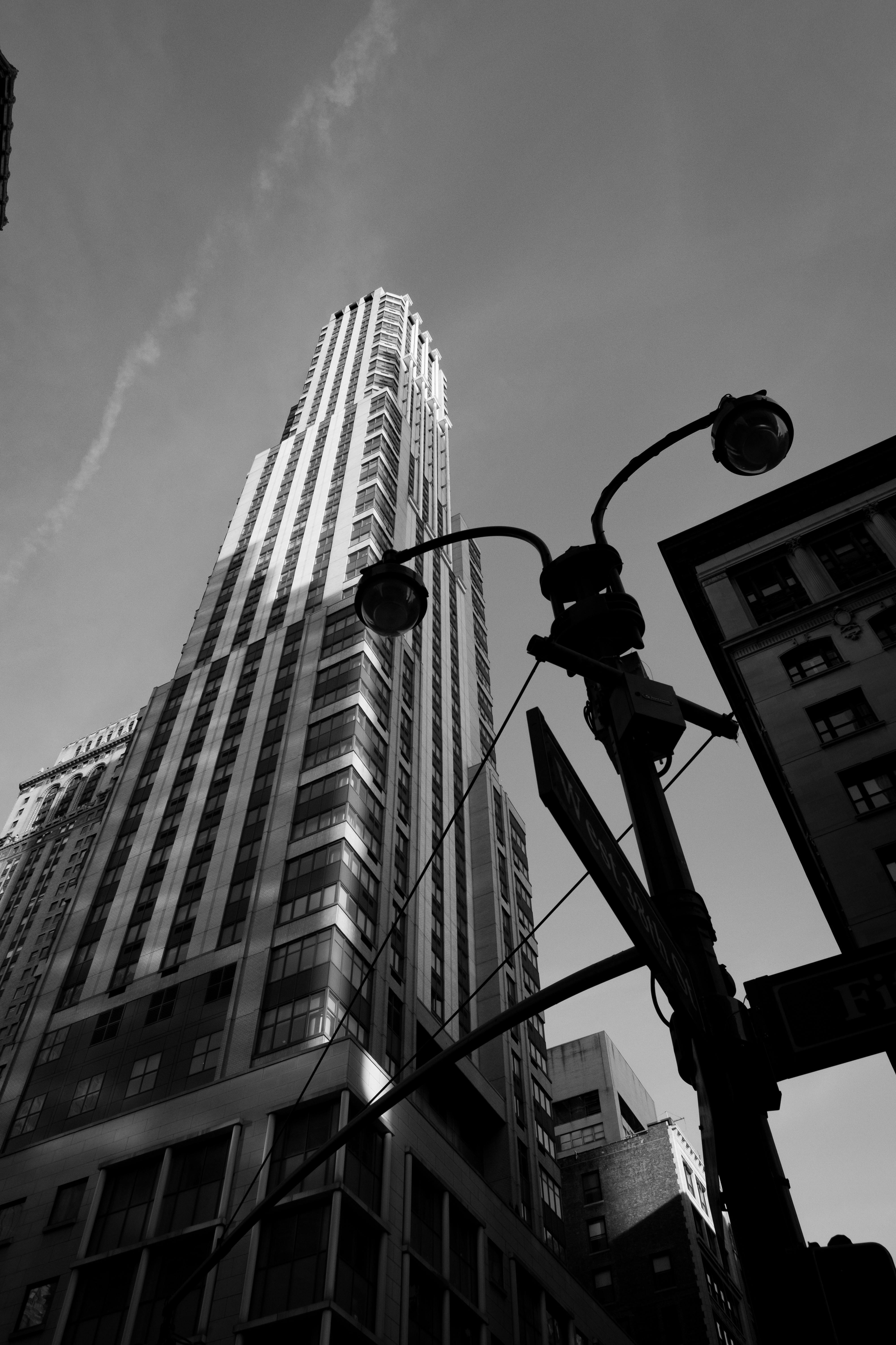 Striking black and white photo of a towering skyscraper from a low angle with a clear sky.