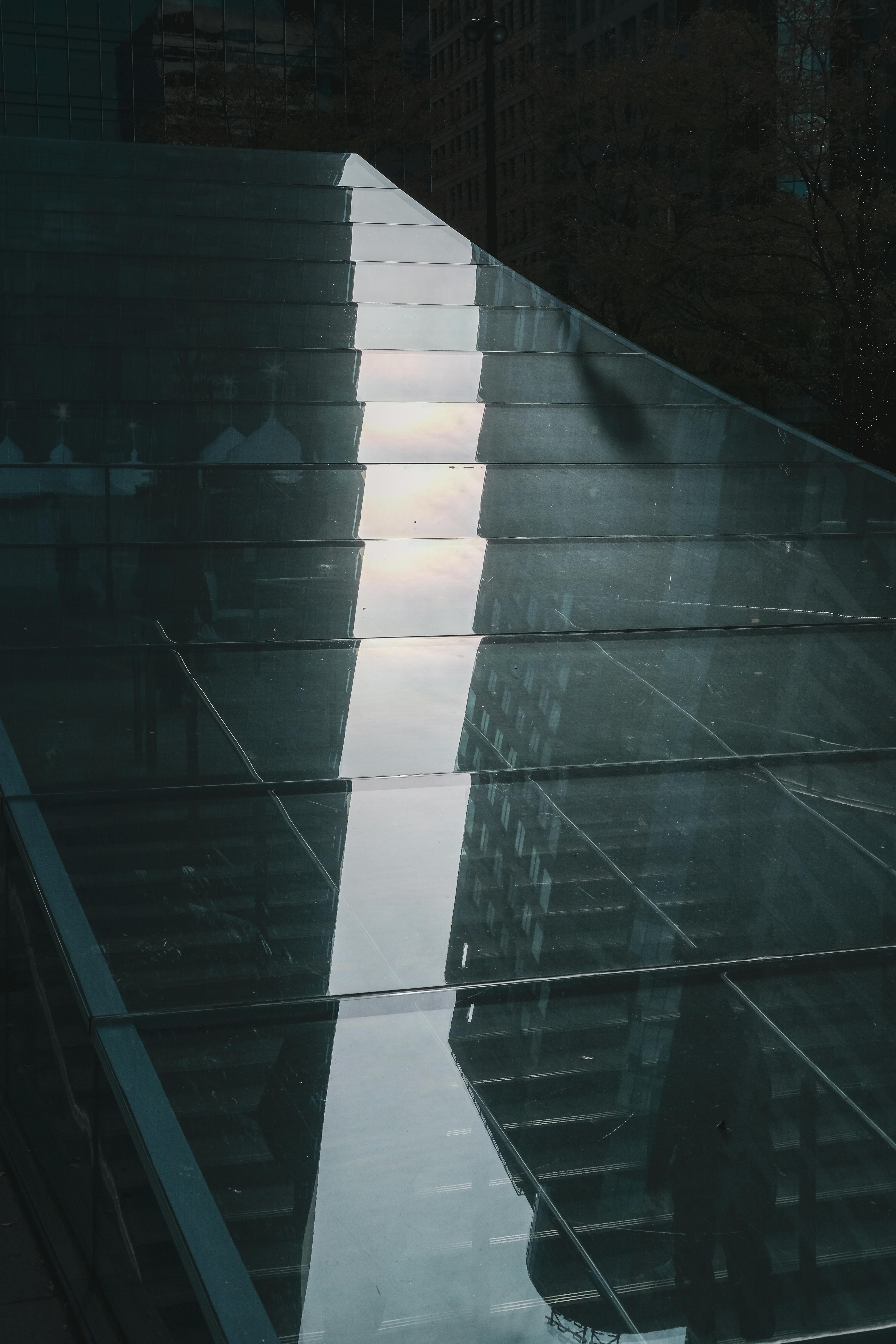 Abstract view of a glass staircase reflecting urban architecture.