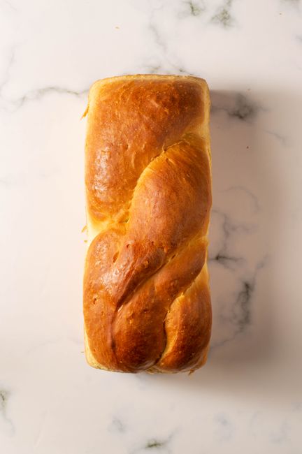A top view of freshly baked homemade brioche bread on a marble countertop.