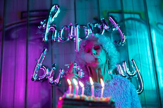 Chic elderly woman celebrates birthday with neon joy and trendy style.