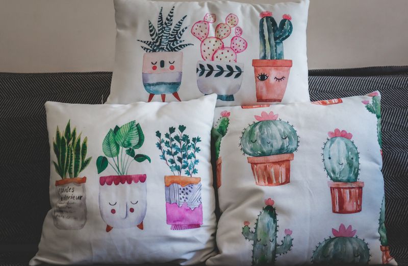 A collection of artistic plant-themed throw pillows on a sofa.