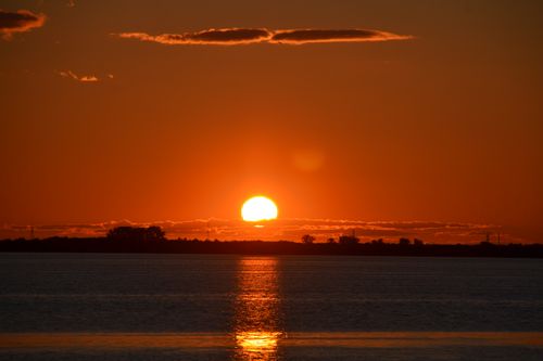 Free Stunning sunset with orange skies reflected on tranquil ocean waves, evoking peace and serenity. Stock Photo